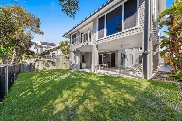 A two-story house with a balcony, a fenced backyard, and a well-maintained lawn.