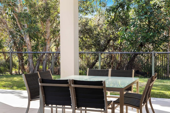 An outdoor patio with a glass-top table and six chairs.