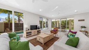 A modern living room with a sofa, coffee table, TV, and a view of the outdoors.