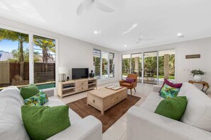 A modern living room with a sofa, coffee table, TV, and a view of the outdoors.