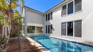A modern house with a swimming pool, large windows, and a wooden deck.