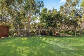 A fenced yard with grass and trees.