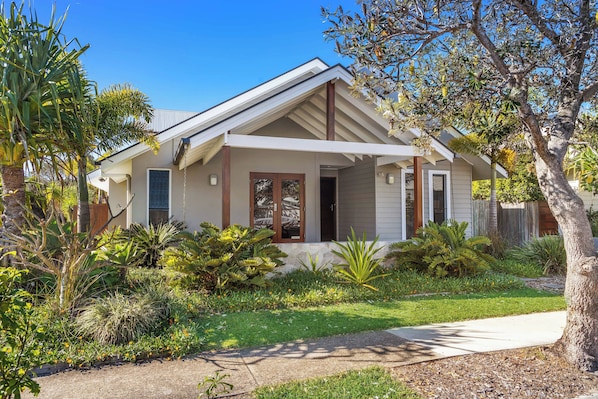 A two-story house with a front porch, surrounded by a well-maintained garden with various plants and a lawn.