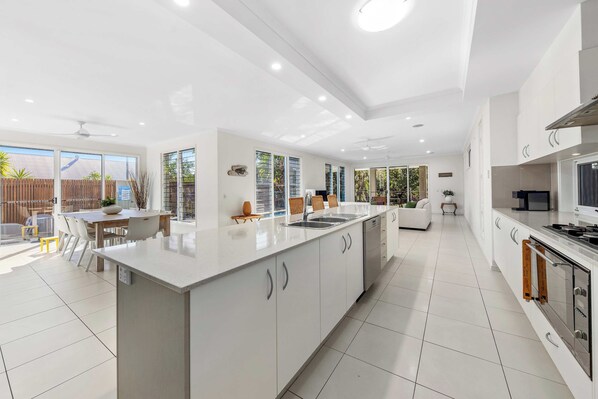 A modern kitchen with a central island, white cabinetry, and a dining area with a table and chairs.