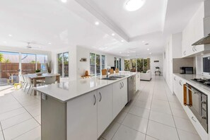 A modern kitchen with a central island, white cabinetry, and a dining area with a table and chairs.
