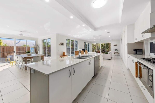A modern kitchen with a central island, white cabinetry, and a dining area with a table and chairs.