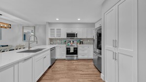 Enjoy cooking in this well-equipped kitchen with stainless steel appliances, a herringbone tile backsplash, and a window above the sink.