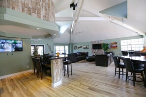 A spacious living area with a high ceiling, a stone accent wall, a dining area with a large table, and a seating arrangement. - ✪MODERN & SPACIOUS 3BD/2BA VILLA✪ Close to Disney! (kissimmee)