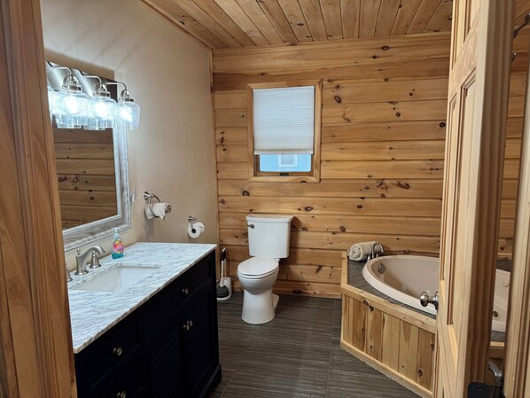 Een badkamer met houten lambrisering, een marmeren wastafel, toilet en bad.