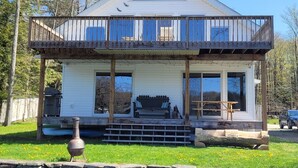 A two-story house with a balcony, large windows, and a front porch. - Lakefront Cottage - Dog Friendly (Thompson)