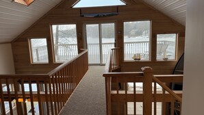 A wooden cabin with a sloped roof, large windows, and a wooden staircase leading to a deck. - Lakefront Cottage - Dog Friendly (Thompson)