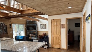 A spacious living area with a kitchen island, a fireplace, and a dining table. - Lakefront Cottage - Dog Friendly (Thompson)