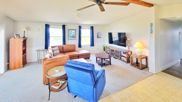 A living room with a sofa, a blue armchair, a coffee table, a TV, and a bookshelf.