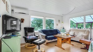 Una sala acogedora con un sillón de cuero, un sofá azul, una mesa de centro de madera y un televisor.