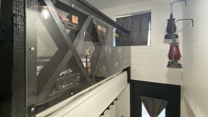 Una escalera con barandilla de vidrio, una puerta blanca y una lámpara en el techo.