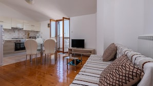 Uma sala de estar moderna com sofá, televisão e área de refeições.