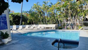 A pool area with lounge chairs and a signboard. - Recently Remodeled, Modern, Nice Condo in a Great Location (Kailua Kona)