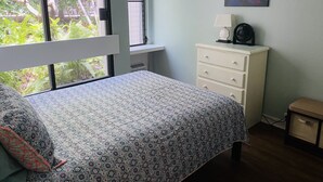A bedroom with a bed, a dresser, a window, and a painting on the wall. - Recently Remodeled, Modern, Nice Condo in a Great Location (Kailua Kona)