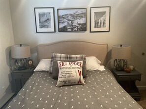 A bedroom with a bed, two nightstands, and three framed pictures on the wall. - Get cozy for the winter in this 3 floor, 4 bedroom rustic ski home (Champion)
