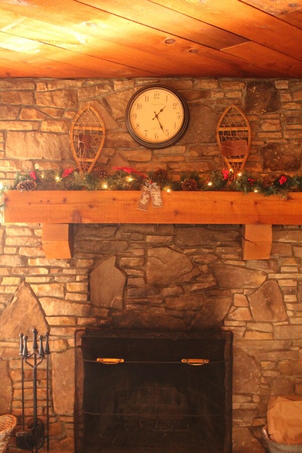 A stone fireplace with a clock above it, a wooden mantel with decorations, and a candelabra to the left. - Get cozy for the winter in this 3 floor, 4 bedroom rustic ski home (Champion)