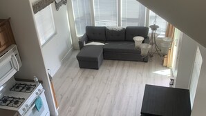 A modern kitchen with a stove and oven, a gray sectional sofa, and a dining area with a chandelier. - Cozy 2 bedroom Cottage by the River  (Ehrenberg)