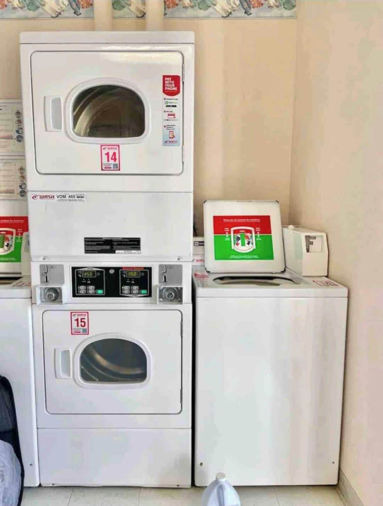 A laundry area with two stacked washing machines, one marked with a price tag of 14 and the other with 15.