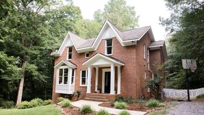 A two-story brick house with a front porch, a small garage, and a basketball hoop in the yard. - Cozy Athens Home on the Brook (Athens)