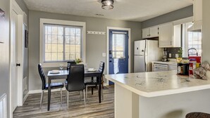 Cocina compacta con comedor, que incluye un refrigerador, un lavamanos y una encimera con diversos objetos.