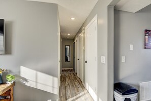 Stylish hallway with a herringbone floor, white doors, and a small potted plant.
