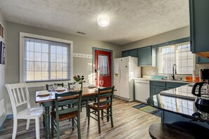 Kitchen with central island, dining area, and red-framed door.