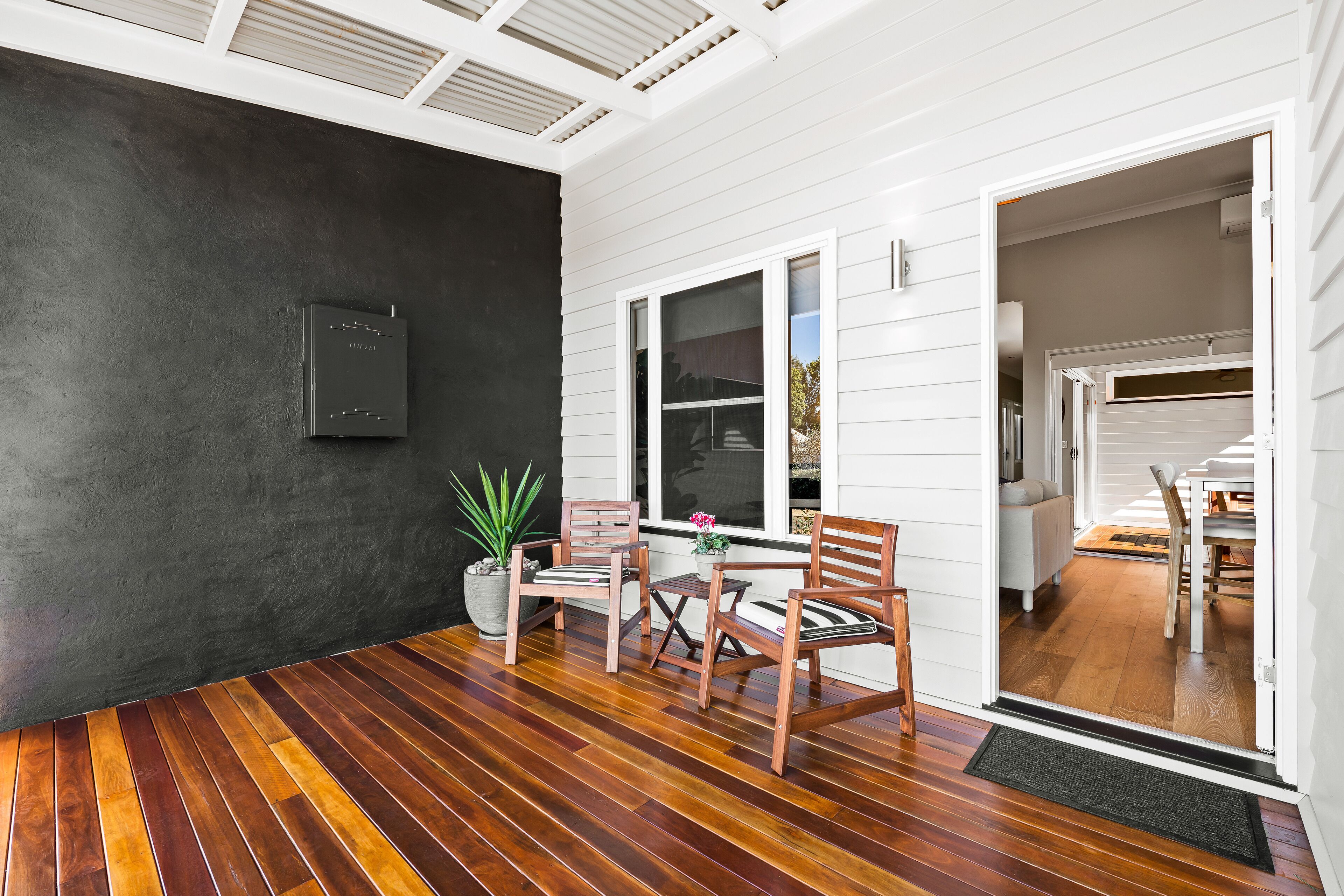 Une pièce avec un plancher en bois, une plante en pot et une chaise près d’une fenêtre.