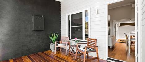 Une pièce avec un plancher en bois, une plante en pot et une chaise près d’une fenêtre.