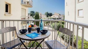 A balcony with a round table, chairs, and a bottle. - Les Villageoises by Interhome (Le Barcarès)