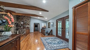A spacious hallway with wooden flooring, a brick accent wall, and a large wooden cabinet.
