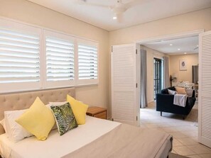 Een slaapkamer met een bed, nachtkastjes en uitzicht op een andere kamer.