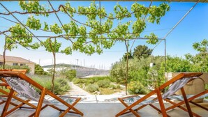 Una terraza con dos sillas de madera y vistas a un jardín y un paisaje lejano.