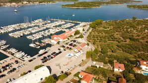 Vista aérea de un puerto deportivo con numerosas embarcaciones amarradas, rodeado de edificios residenciales y vegetación.