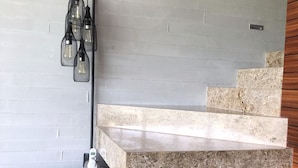 A staircase with a stone finish, a wooden cabinet with drawers, and a wall-mounted light fixture. - Beautiful Golf Course Views - Relax! (Nuevo Vallarta)