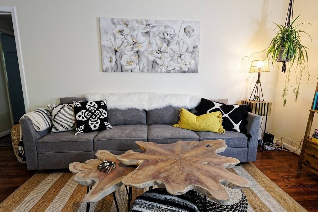 A living room with a gray sofa, a wooden coffee table, and a floral painting on the wall.