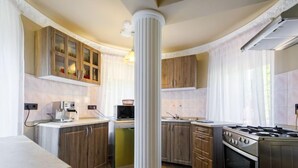 A modern kitchen with wooden cabinets, a central column, a stove, and a dishwasher. - Big Thuja by Interhome (Balatonföldvár)