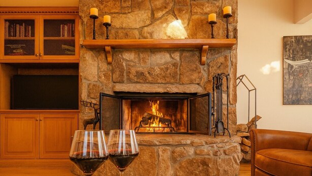 A stone fireplace with a fire, flanked by bookshelves and a leather armchair.