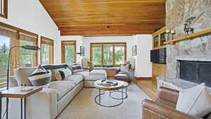 A spacious living room with a large sectional sofa, a round coffee table, and a stone fireplace.