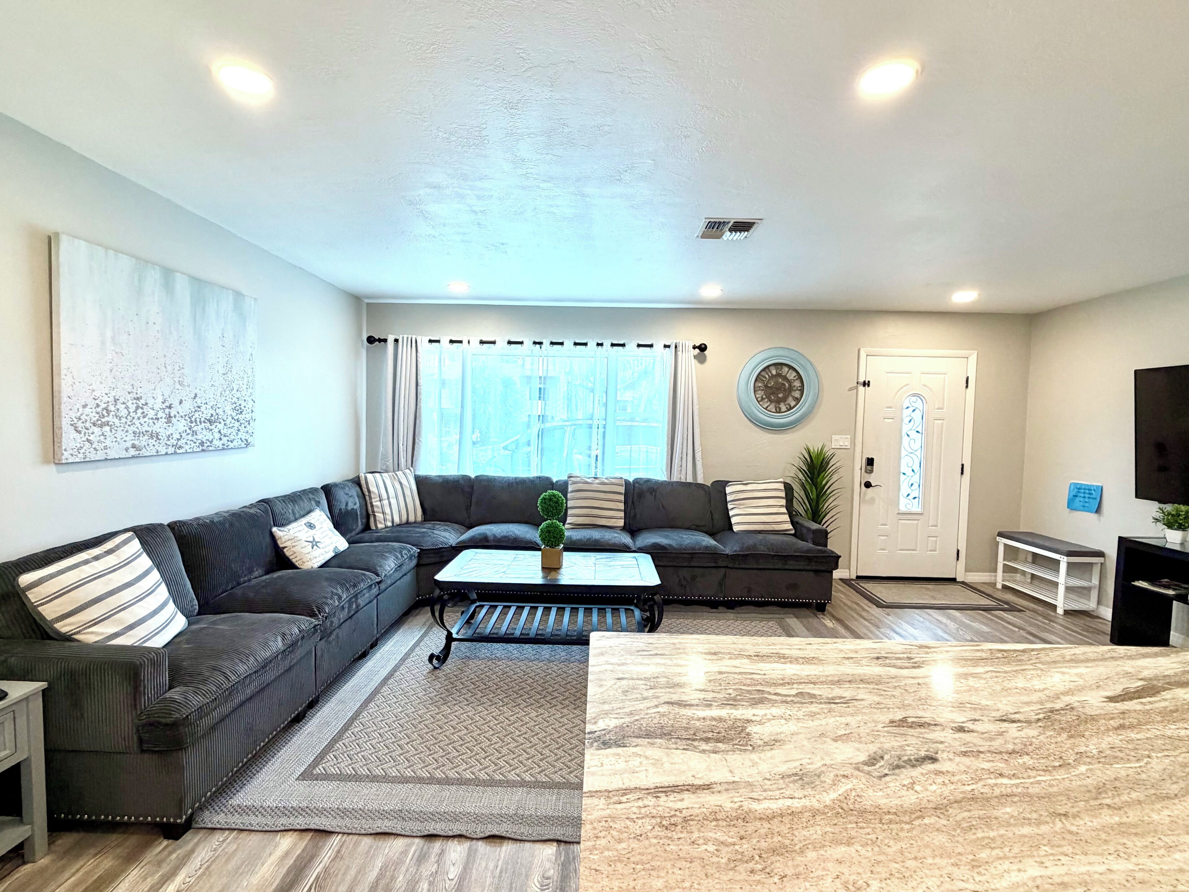 A living room with a sectional sofa, a coffee table, a TV, and a door with a decorative window.