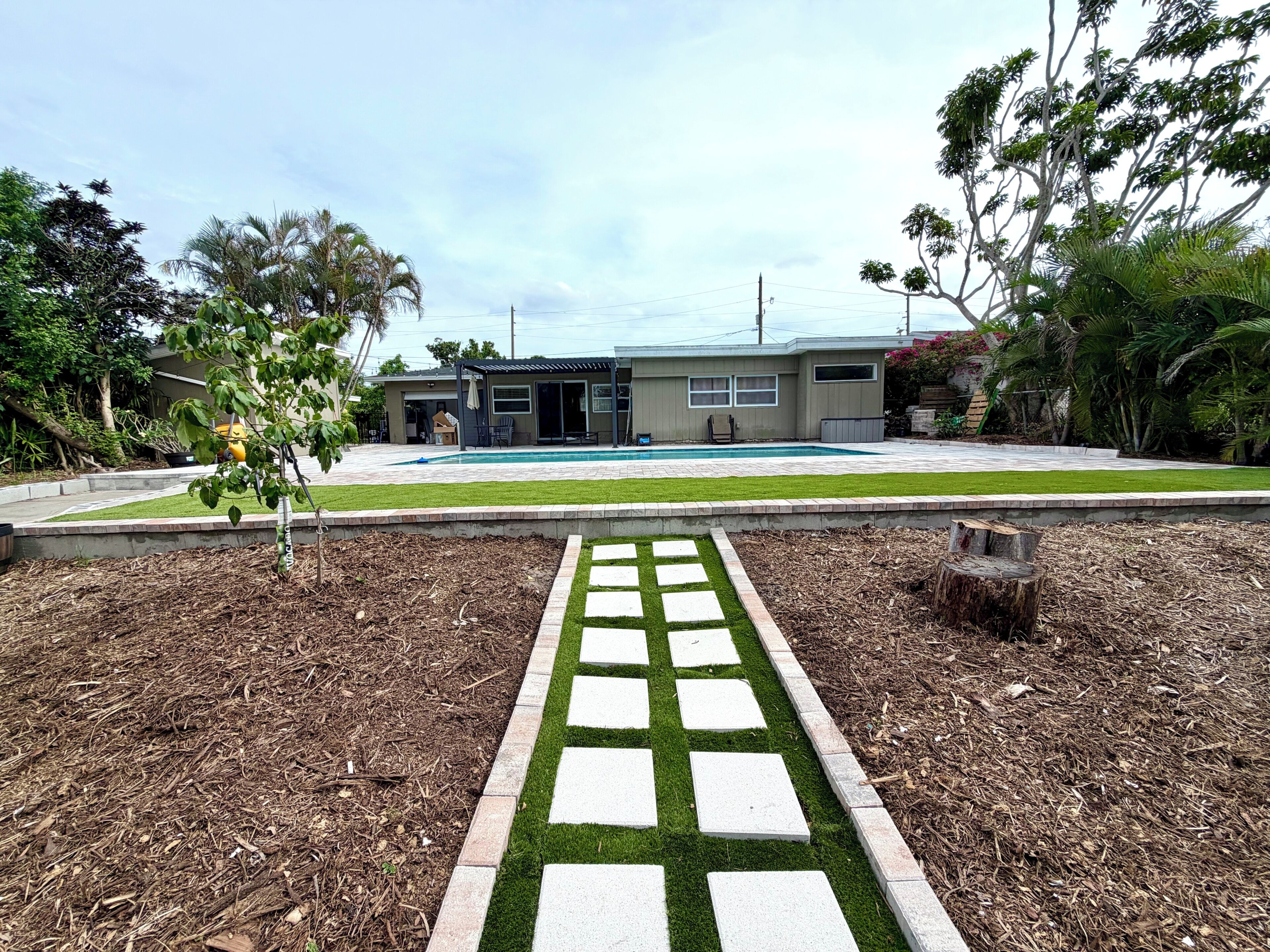 A residential property with a swimming pool, a covered patio, and a well-maintained lawn.
