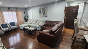 A living room with a stone accent wall, a brown leather sofa, a patterned sofa, and a coffee table.