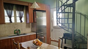 Una cocina con armarios de madera, un refrigerador de acero inoxidable, una mesa de comedor con sillas y un frutero.
