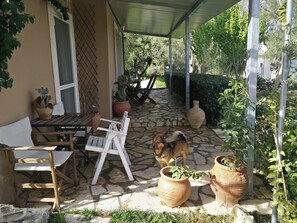 Un porche cubierto con suelo de piedra, mobiliario de madera y plantas en macetas.