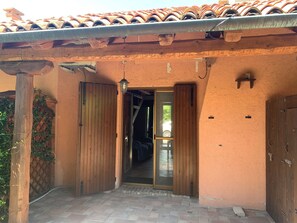 An entrance with a wooden door and a glass door, leading to a covered patio area with a tiled roof. - Beautiful and Quiet Villa In Residence In The Po Delta Oasis (Porto Viro)
