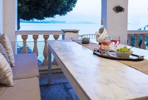 A terrace with a marble table, a bowl of grapes, and a bottle of wine. - Beachfront Spetses Spectacular Fully Equipped Traditional Villa Families,groups (Spetses)