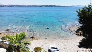 A coastal view with clear water, a boat on the shore, and a distant shoreline. - Beachfront Spetses Spectacular Fully Equipped Traditional Villa Families,groups (Spetses)